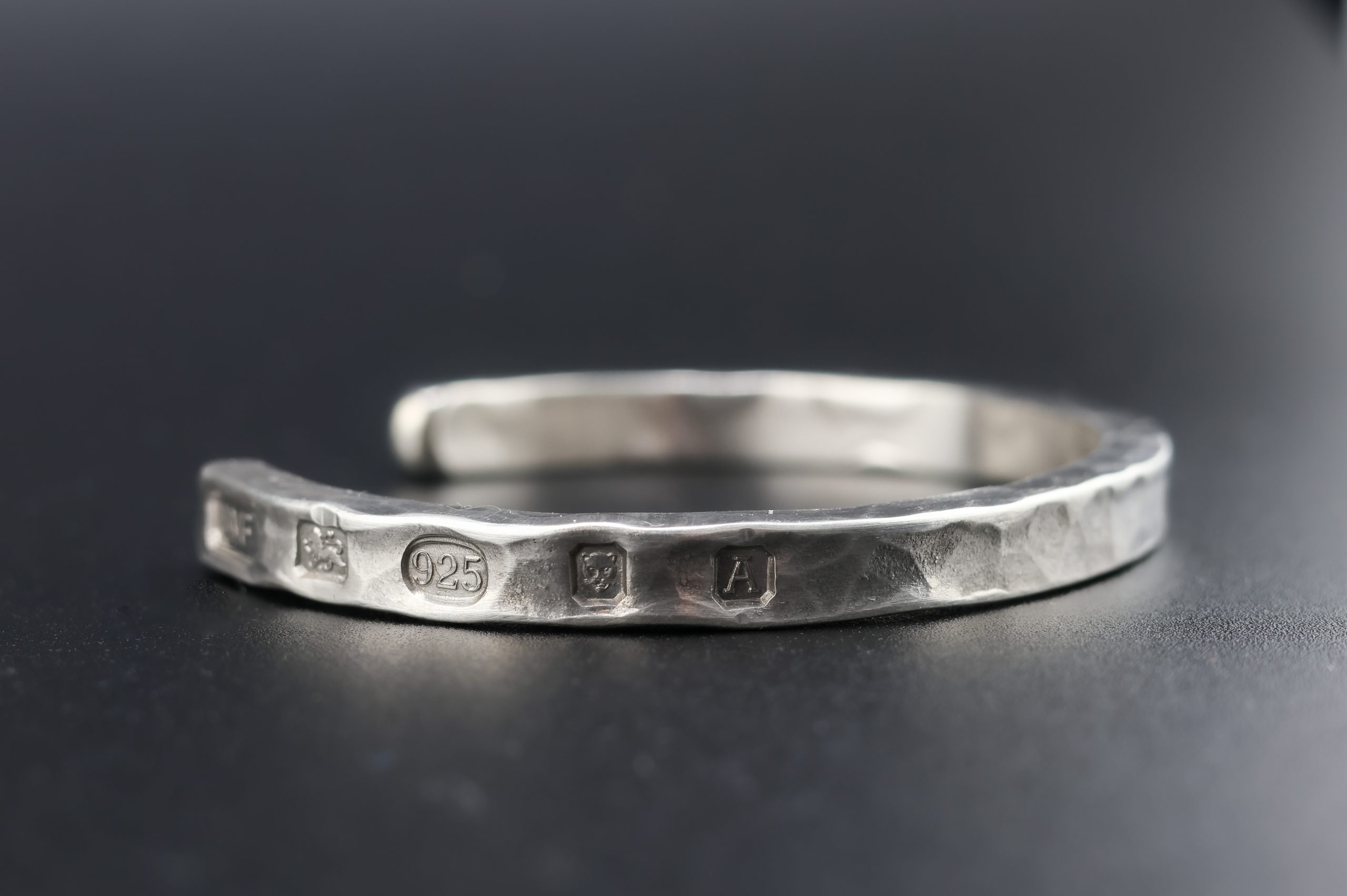 9E2A1926 Heavy sterling silver men's open cuff bracelet. It is finished in a hammered texture and incorporates large struck hallmarks on the outside of the cuff. It makes a perfect gift for men who value quality. Handmade in Devon, Newton Abbot by award winning goldsmith, James French at JWF Unique Designs