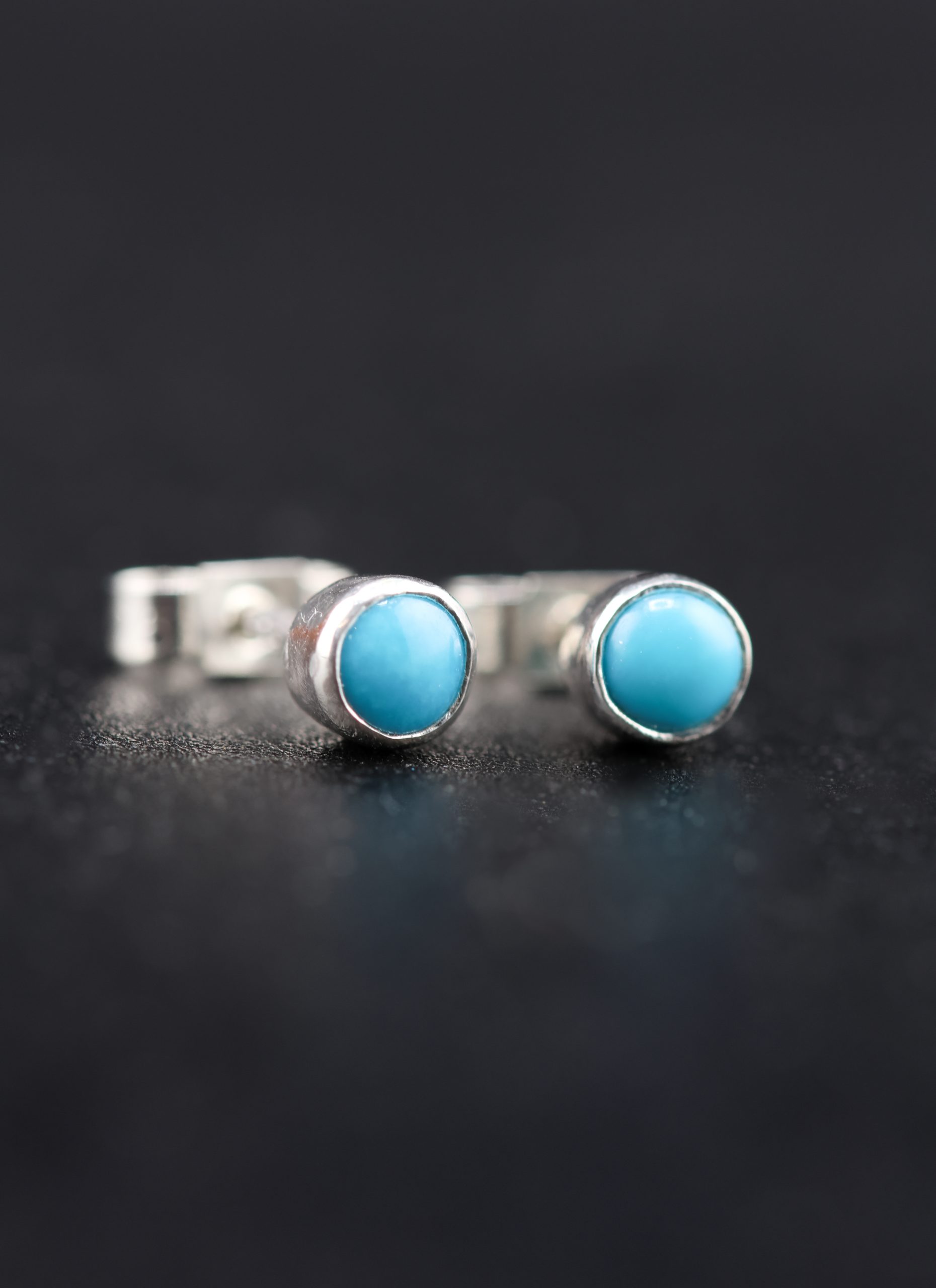 9E2A2998 Turquoise stud earrings in sterling silver. Handmade in Devon, by award winning goldsmith jeweller James French at JWF Unique Designs. The Turquoise stones are flush set into the stud earrings and come with sterling silver butterfly backs. The perfect gift, handmade jewellery.