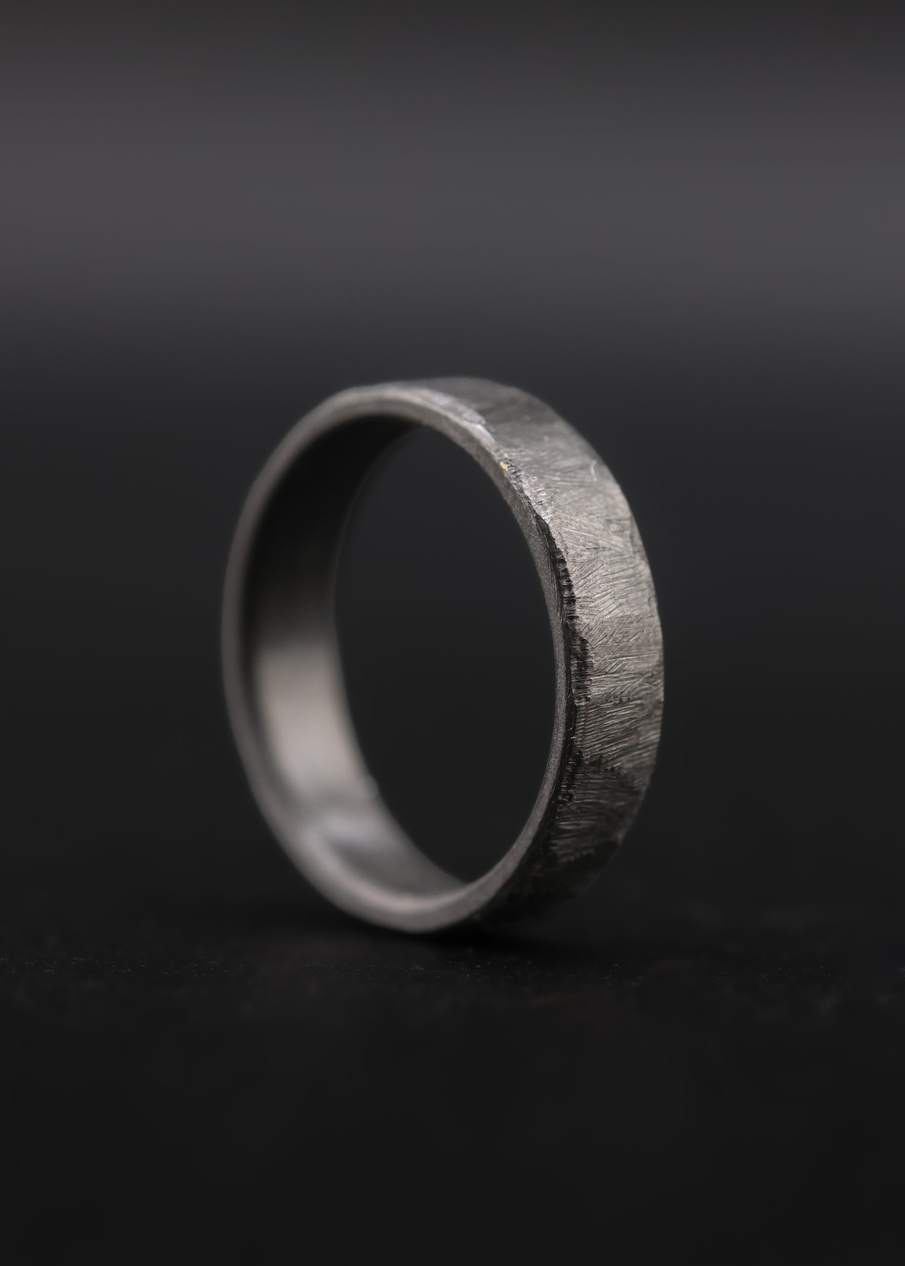 9E2A6511 zirconium wedding rings in 3mm and 5mm width. The texture is a cast design giving the wedding rings a rustic texture with black style. a unique wedding ring handmade in devon by jeweller James French.