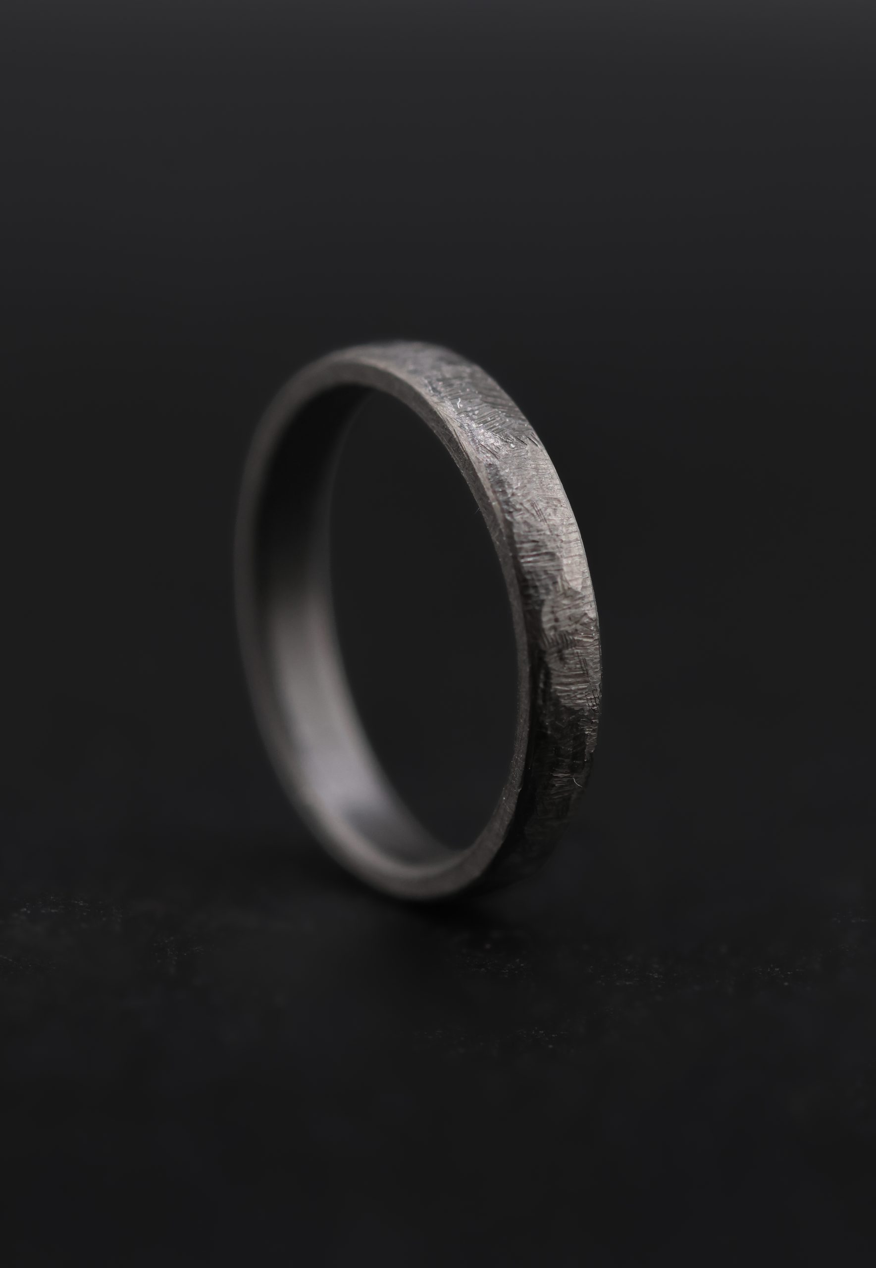 9E2A6516 zirconium wedding rings in 3mm and 5mm width. The texture is a cast design giving the wedding rings a rustic texture with black style. a unique wedding ring handmade in devon by jeweller James French.