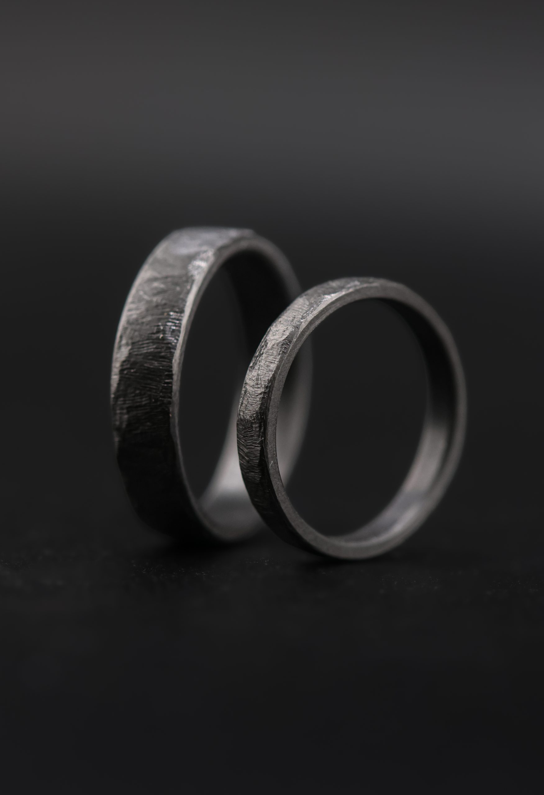 9E2A6522 zirconium wedding rings in 3mm and 5mm width. The texture is a cast design giving the wedding rings a rustic texture with black style. a unique wedding ring handmade in devon by jeweller James French.