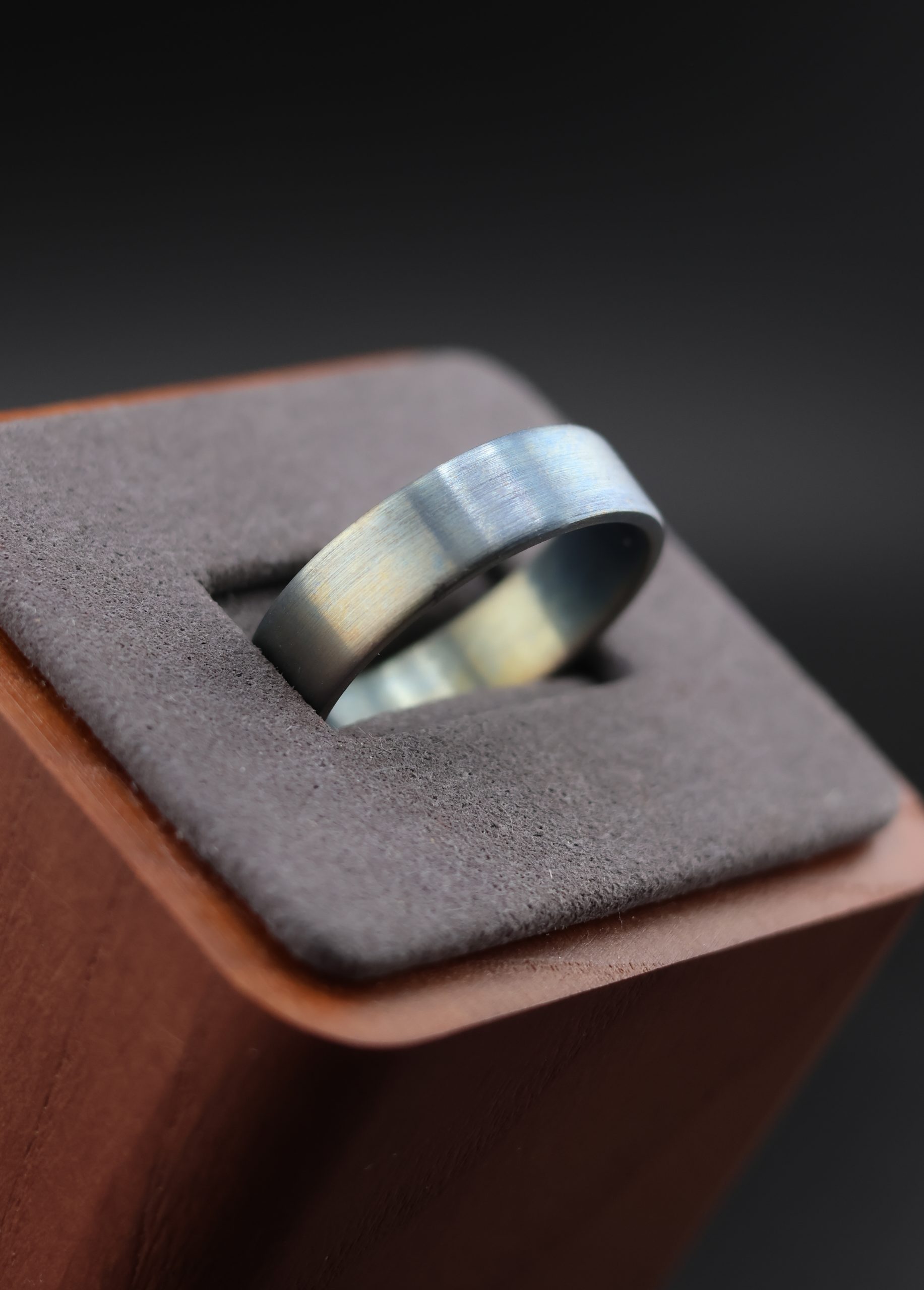 9E2A3646 Anodised titanium wedding ring with flat profile. Subtle colour variation created through anodising. Each ring has a unique finish. Lightweight and durable titanium band. Handmade in Devon, UK.