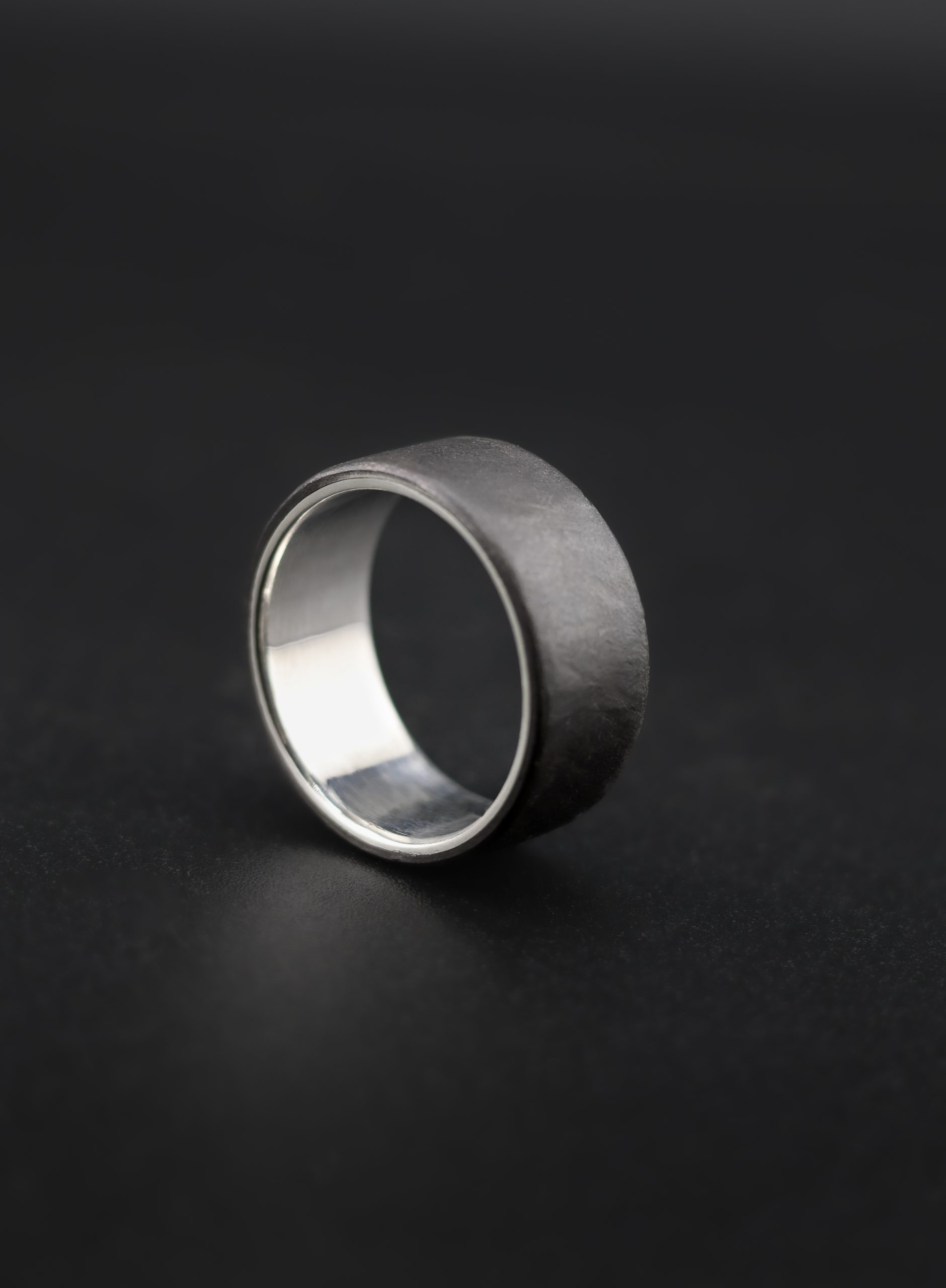 9E2A4151 Black Zirconium Wedding Ring with a sterling silver liner. 7mm width, matte texture. Handmade in the UK by award winning goldsmith, JWF Unique Designs. Perfect unique black ring for men.