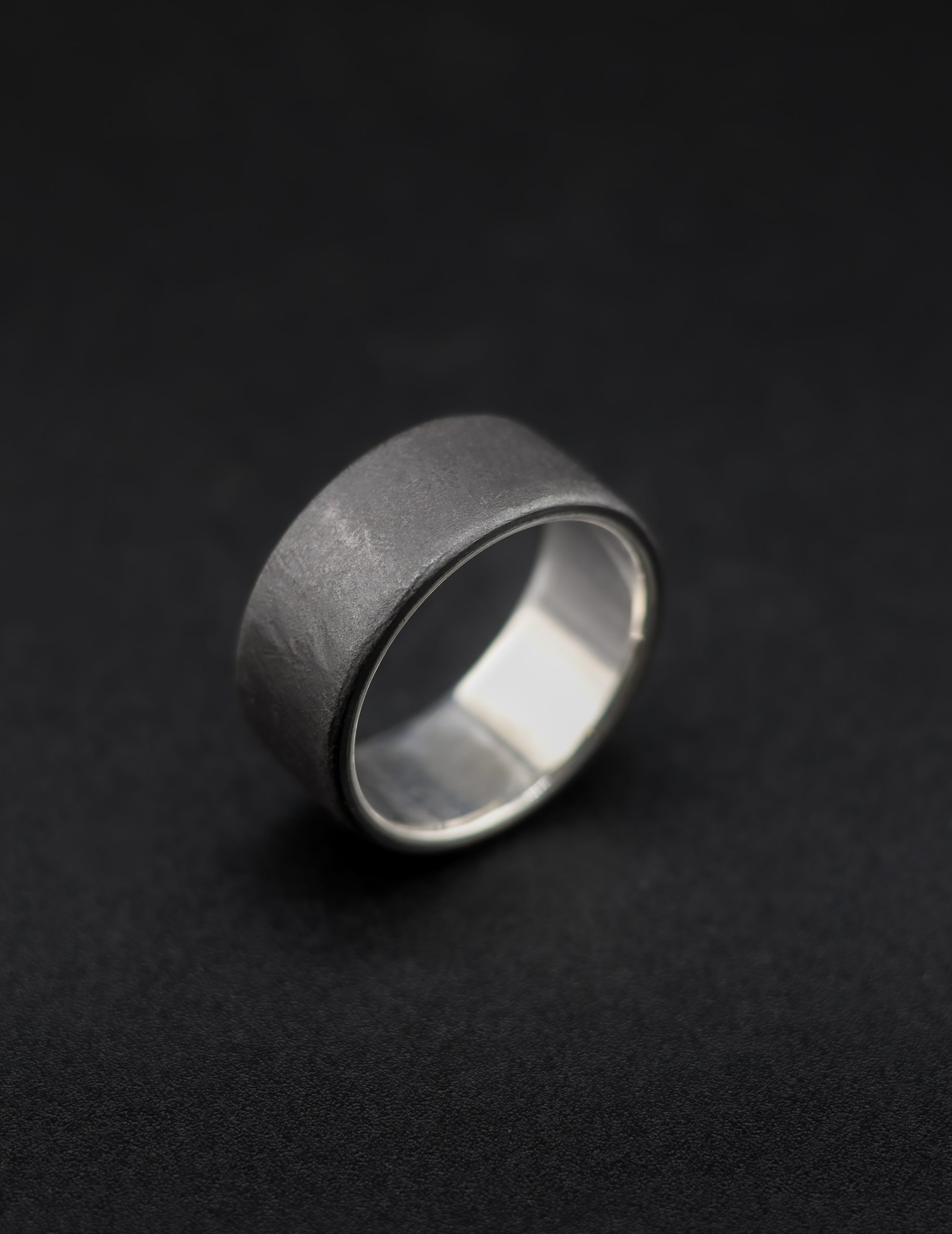 9E2A4152 Black Zirconium Wedding Ring with a sterling silver liner. 7mm width, matte texture. Handmade in the UK by award winning goldsmith, JWF Unique Designs. Perfect unique black ring for men.