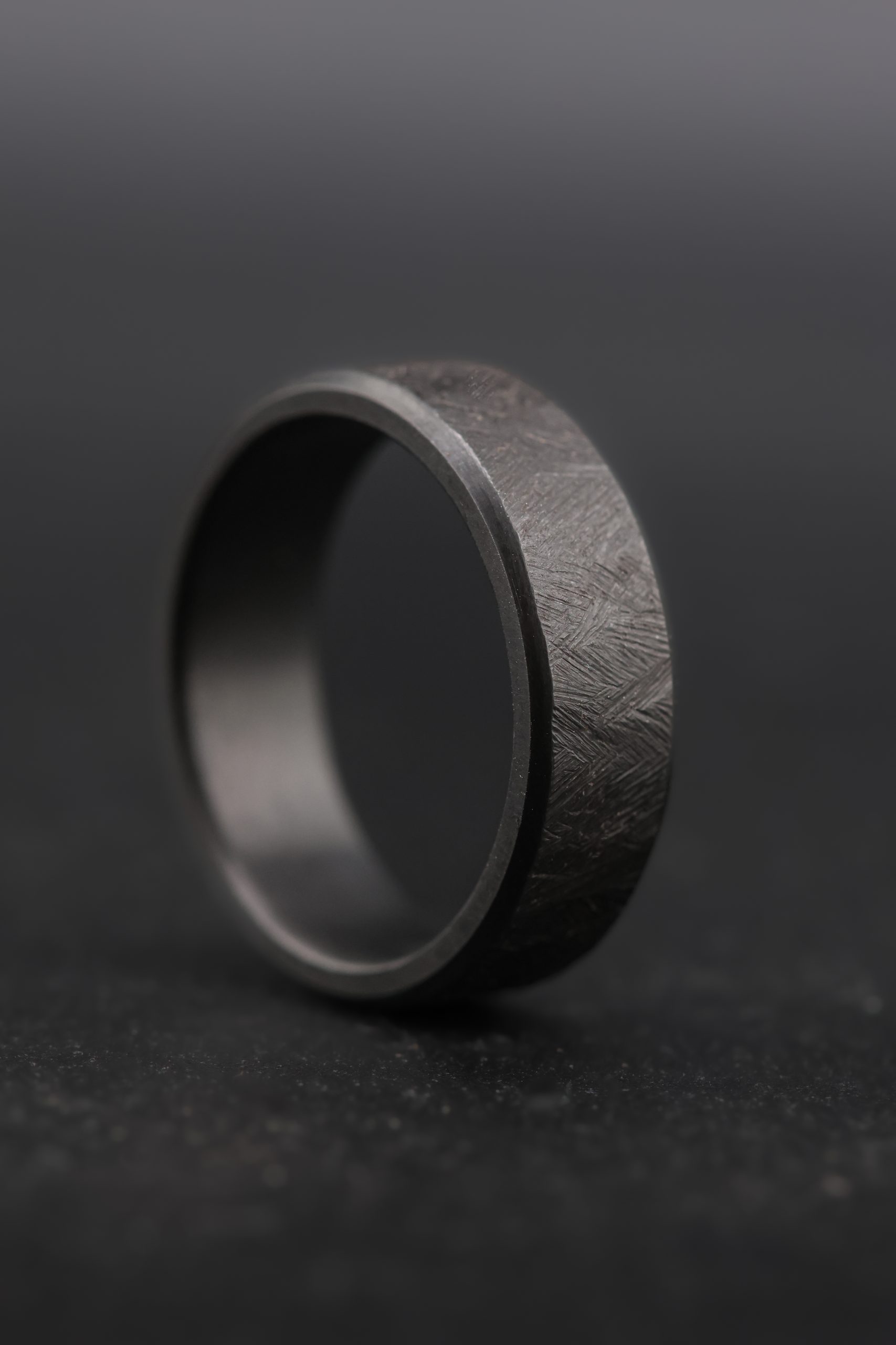 9E2A4193 Black zirconium wedding ring with cast texture finish. Flat profile band with chamfered edges. Dark coloured men's wedding ring. Available in widths from 5mm to 10mm. Handmade in Devon, UK by award-winning goldsmith James French.