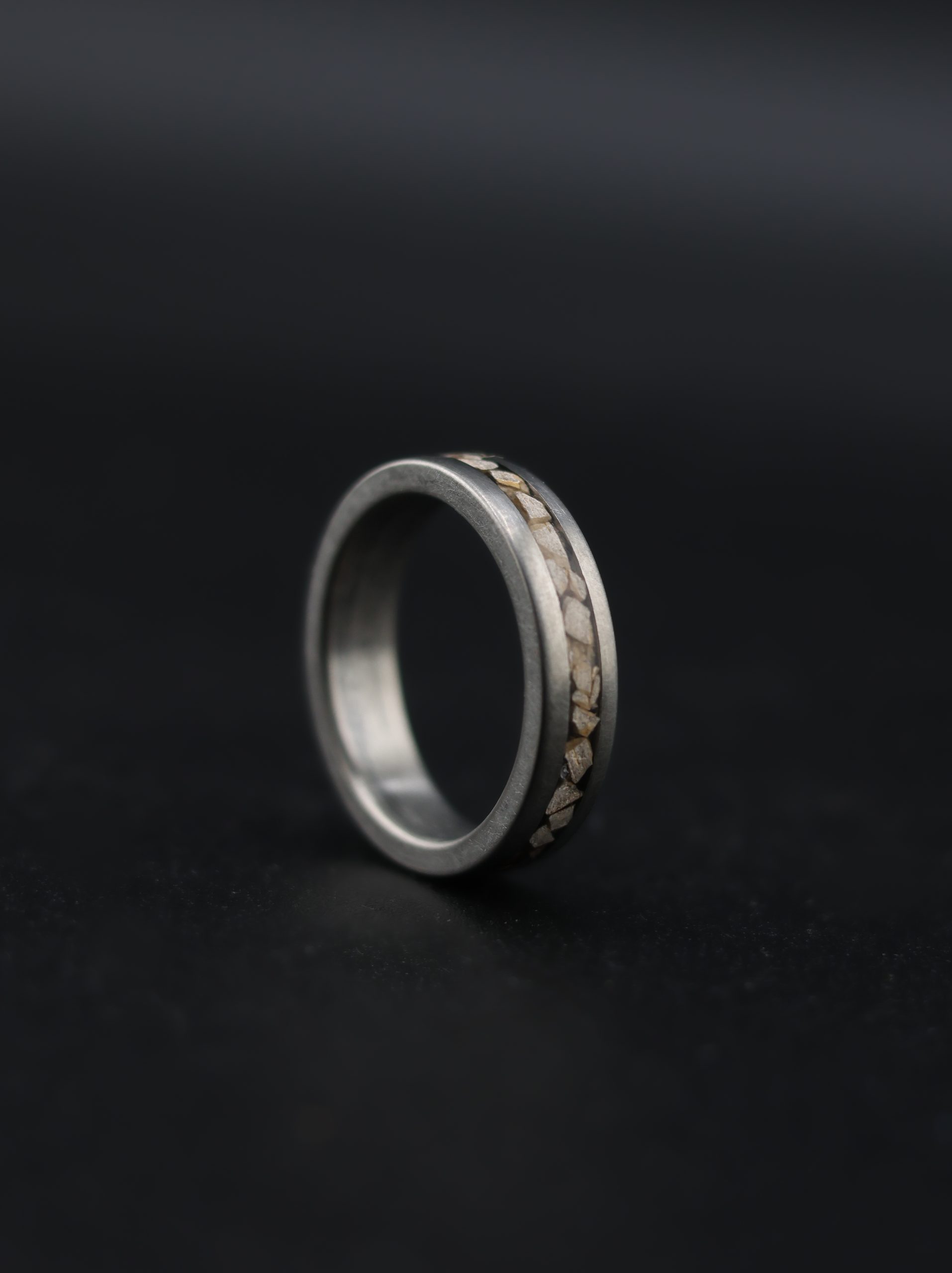 9E2A3864 Titanium dinosaur fossil wedding ring. 5mm wide band featuring certified fossilised Stegosaurus dinosaur bone and Lightweight and durable men's wedding ring. Handmade in Devon, UK by award-winning goldsmith James French.
