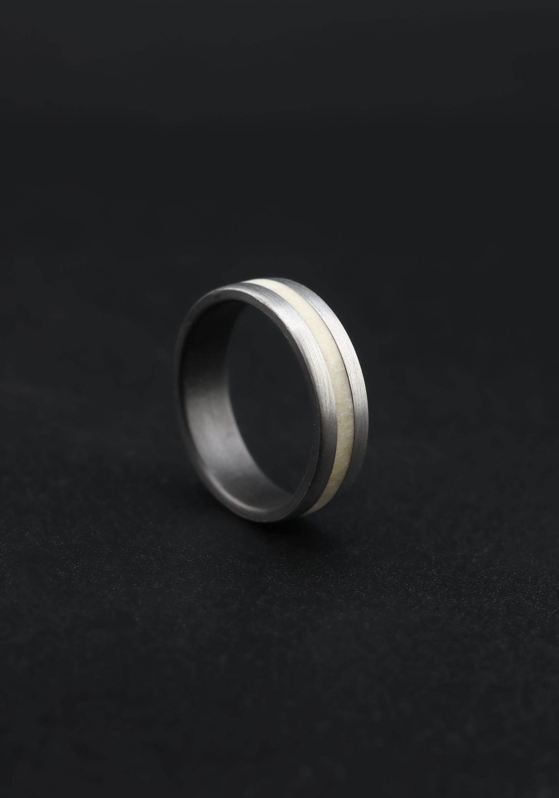 9E2A4416 Titanium wedding ring with natural deer antler inlay. 6mm width, flat profile with rounded corners. Handmade in the UK by award winning jeweller James French. Perfect for a unique and durable wedding ring