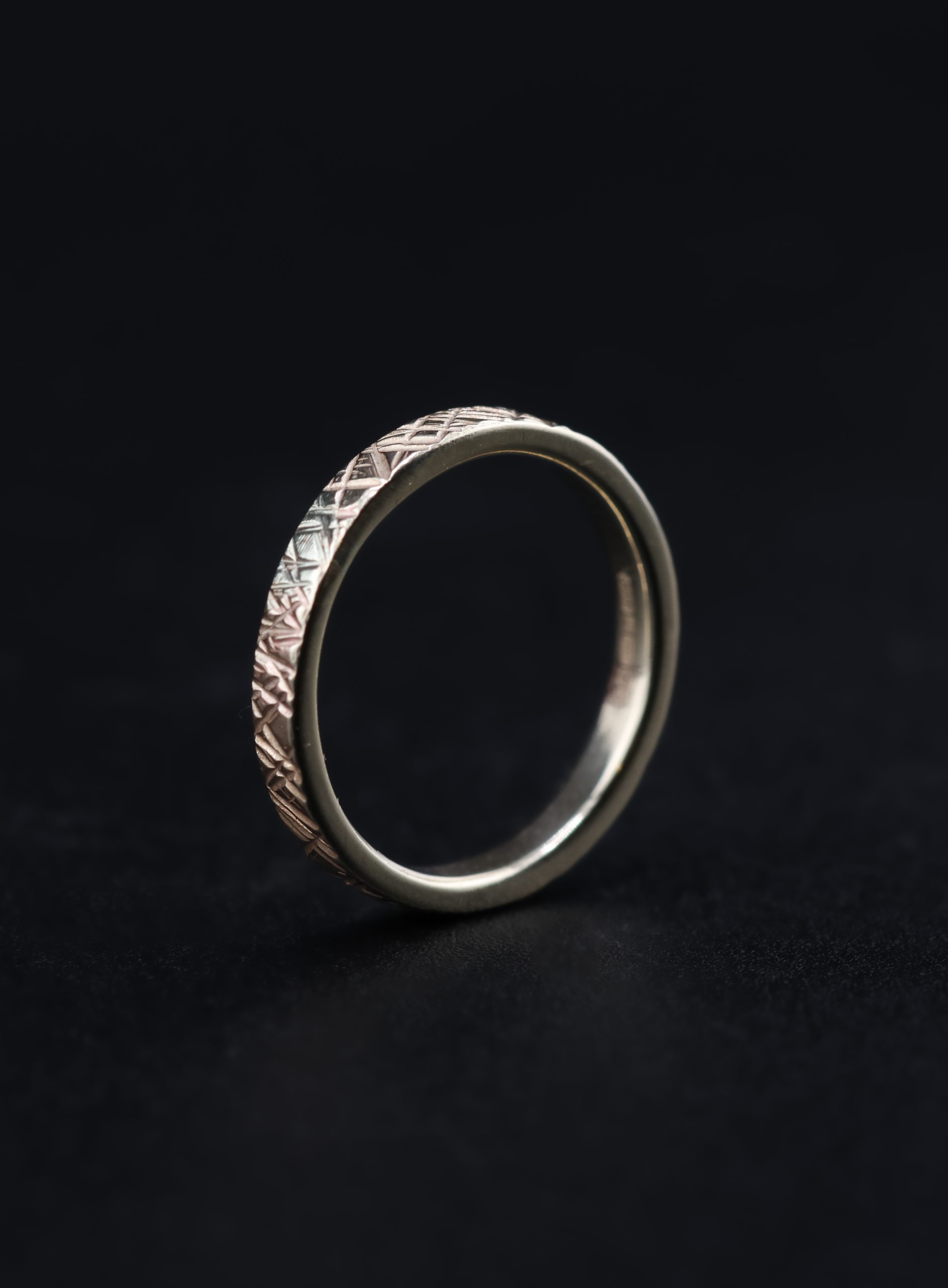 9E2A5772 A slim 2.5mm wedding ring made from polished 9ct yellow gold. The flat profile features an angular Prism hammered texture that catches and reflects the light. This textured yellow gold wedding ring is handmade in Devon by goldsmith James French.