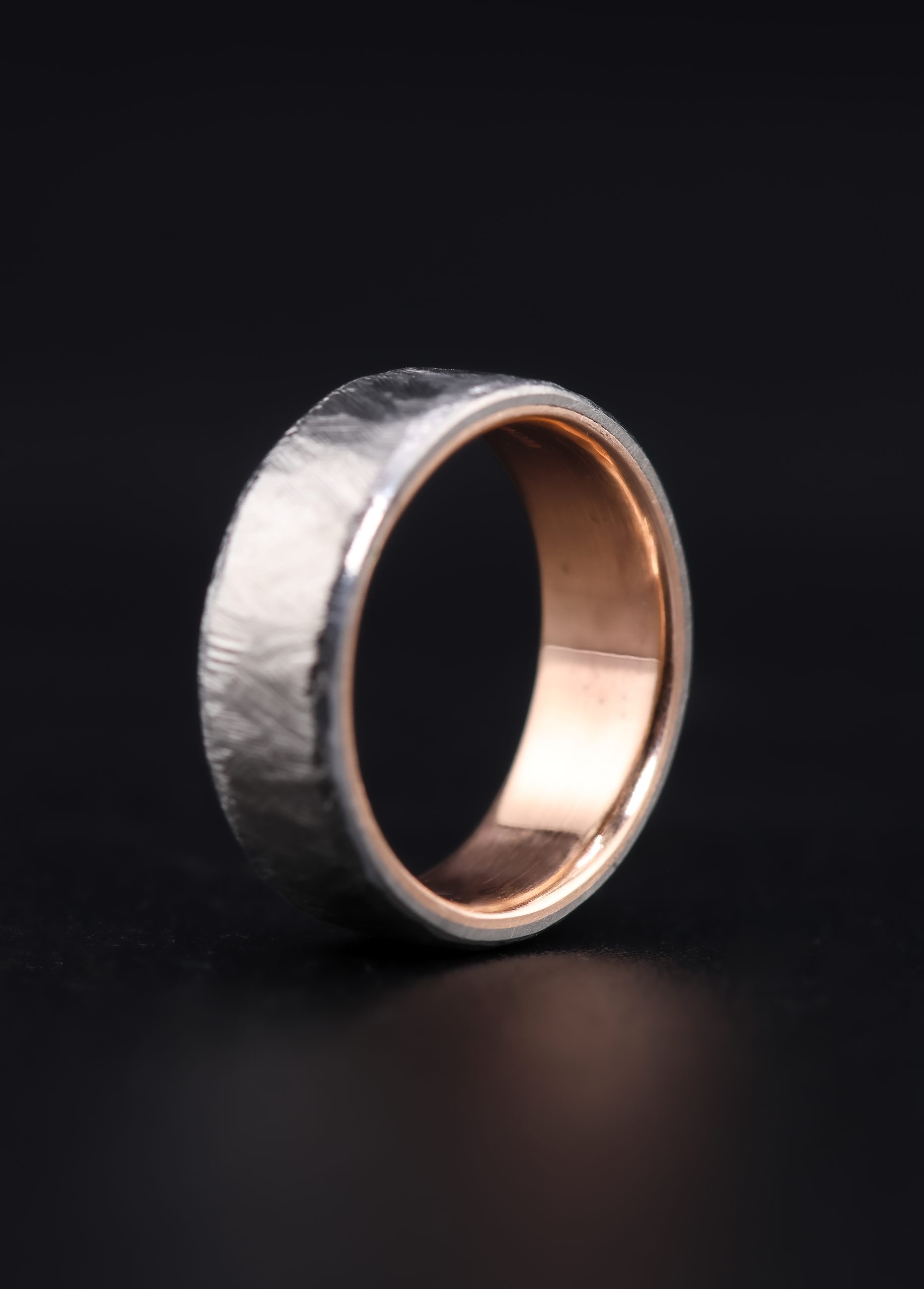 9E2A5844 A men’s titanium wedding ring with a textured cast finish, flat profile and solid 9ct rose gold liner. This 7mm titanium wedding ring is lightweight, durable and handmade by James French at JWF Unique Designs in Devon.