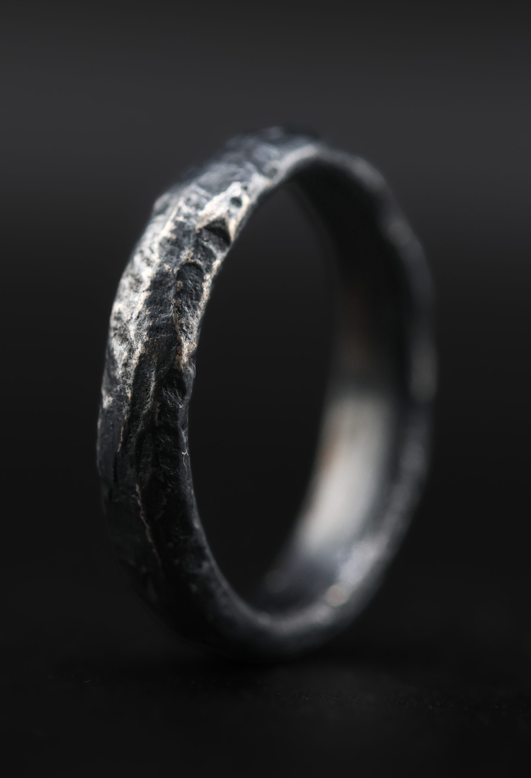 9E2A6406 A men’s sterling silver wedding ring with a dark riven texture and D-shape profile. The sand cast ring is handmade in Devon by goldsmith and silversmith James French.