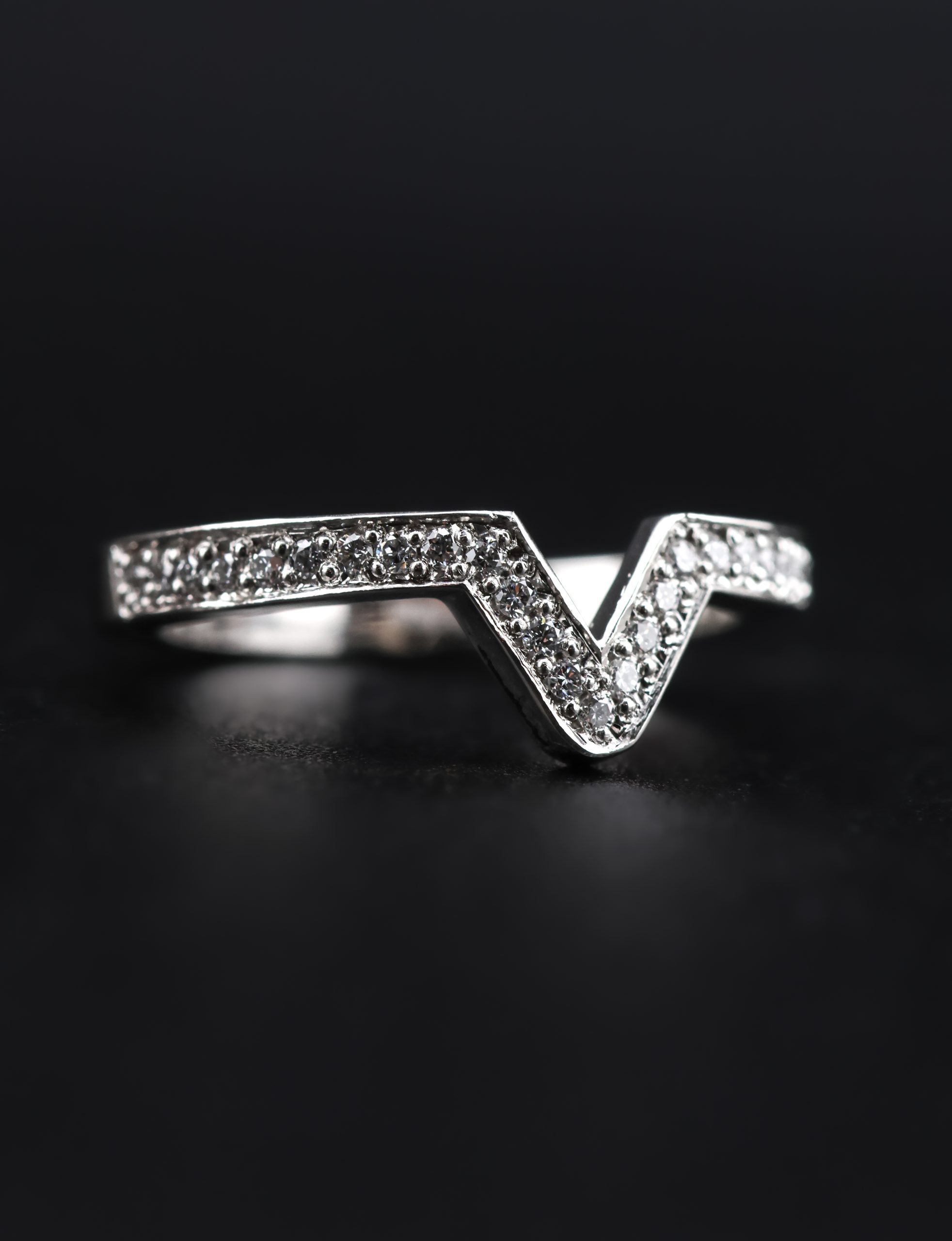 9E2A6431 A platinum diamond chevron wedding ring with micro-grain set natural diamonds and a defined V-shaped centre. The 2.5mm ring is designed to fit around an engagement ring. It is handmade in Devon by goldsmith and silversmith James French.